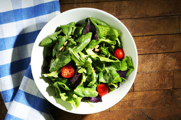 Fresh green salad in bowl on wooden table