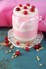 Raspberry milk dessert in glass jar, on color wooden background