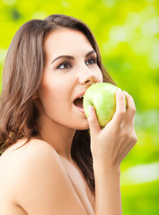 Young woman eating apple, outdoors