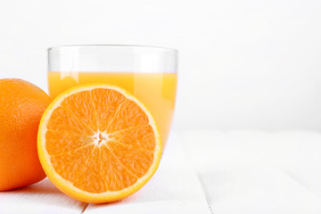 Glass of fresh orange juice on white wooden table