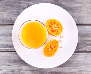 Glass of juice and ripe sweet tangerine on wooden table