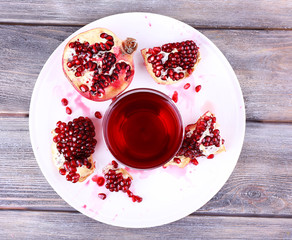 Ripe pomegranate and glass of juice on wooden table