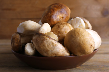 Fototapeta premium Wild mushrooms on plate on wooden background