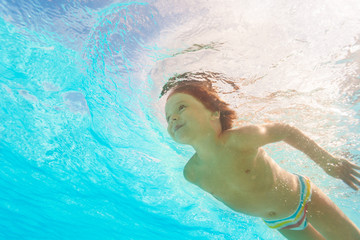 Smiling boy swimming under crystal-clear water © Sergey Novikov