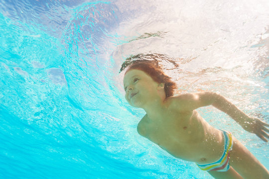 Smiling boy swimming under crystal-clear water