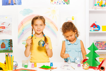 Smiling girls paint New Year balls for Xmas tree