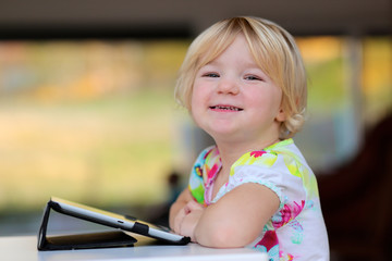 Toddler girl playing with tablet pc at home