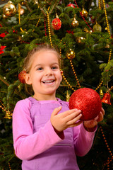 Adorable toddler girl holding decorative Christmas toy ball