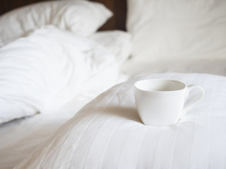 Unmade Bed and pillow with coffee breakfast in the morning