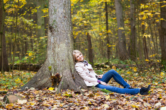 Beautiful woman sitting under the tree in autumn
