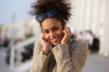 Happy young woman listening to music on headphones outdoors