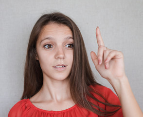 Happy young woman shows an index finger upwards