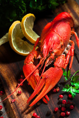 Boiled crayfishes on cutting board with lemon, pepper and parsle