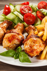 Grilled chicken legs with chips and vegetables