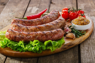 Grilled sausage on a board with vegetables and sauce