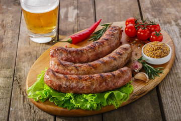 Grilled sausage on a board with vegetables and sauce