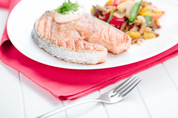 Grilled Salmon with Fresh vegetables on red background