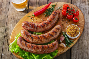 Grilled sausage on a board with vegetables and sauce - 73165571