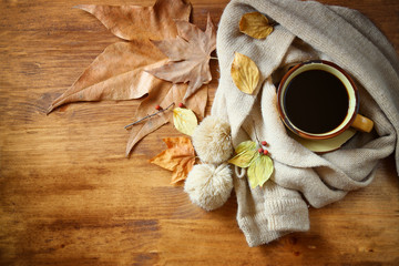 Top view of Cup of black coffee with autumn leaves, a warm scarf