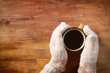 Fototapeta na wymiar Top view of Female hands with a hot coffee, on wooden background