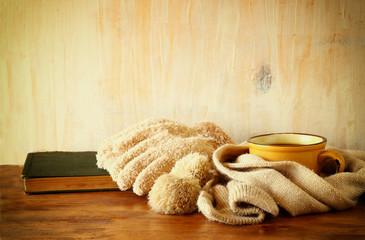 Cup of black coffee with a warm scarf and old book on wooden bac