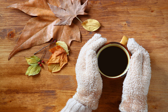 Top view of Female hands with a hot coffee, on wooden background