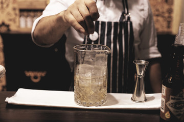 Fototapeta na wymiar Bartender is making cocktail at bar counter, toned image