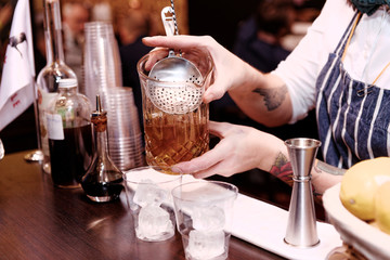 Bartender is making cocktail at bar counter, toned