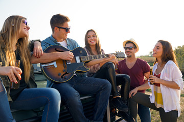 Portrait of group of friends playing guitar and drinking beer.