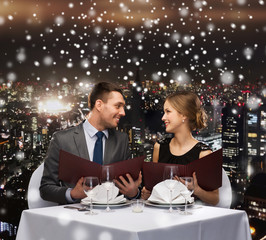 smiling couple with menus at restaurant