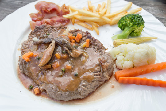 Grilled steaks, French fries and vegetables