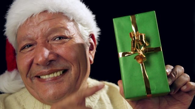 Excited Male Senior With Santa Cap Points At Gift