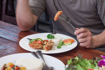 Man eating fried chicken wing on rice