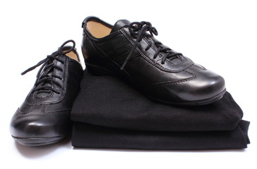 Black shoes on stack of womanly clothes. White background