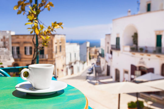Fototapeta A cup of coffee on table with Italian town at the background
