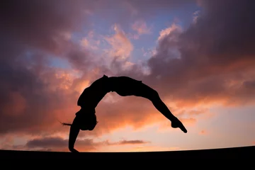 Foto op Plexiglas back handspring of female gymnast in sunset sky © Alex Koch