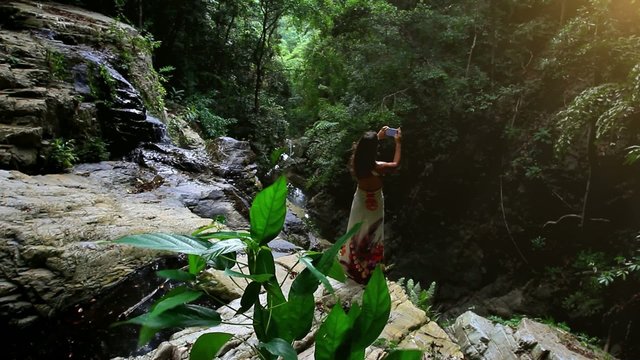 woman tourist taking photo with smart phone in jungle on