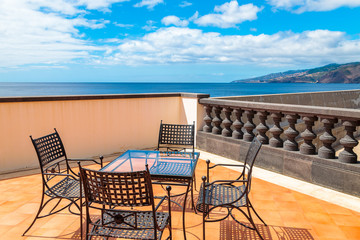 Chairs and table on sunny terrace with sea view, Madeira island