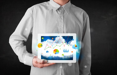 Fototapeta na wymiar Person holding a touchpad with cloud technology and charts