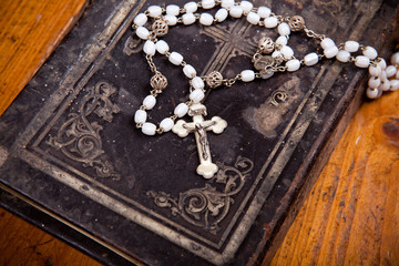 Rosenkranz mit Kruzifix auf schwarzer Bibel,