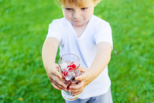 Beautiful toddler boy with glass of berry ice cubes