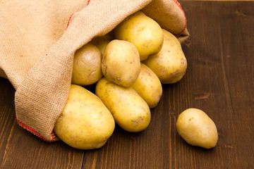 Sack of potatoes on wooden table seen up close