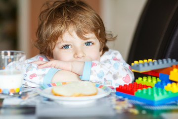 Little kid boy drinking milk and playing with construction block