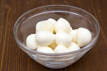 Small mozzarella in bowl on wooden table