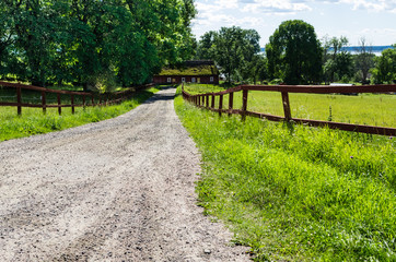 Fototapeta na wymiar Gravel road to a house in a rural landscape.