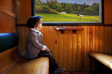 Boy, dressed in vintage coat and hat, sitting in a train