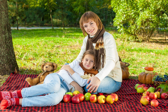 Happy mother with little daughter in autumn park
