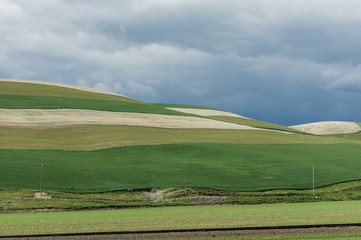 Rolling green farm fields with angry storm