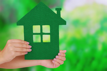 Woman hands holding paper house on bright background