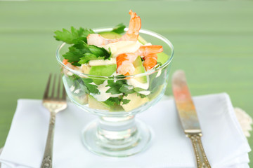 Tasty salad with shrimps and avocado, on wooden background